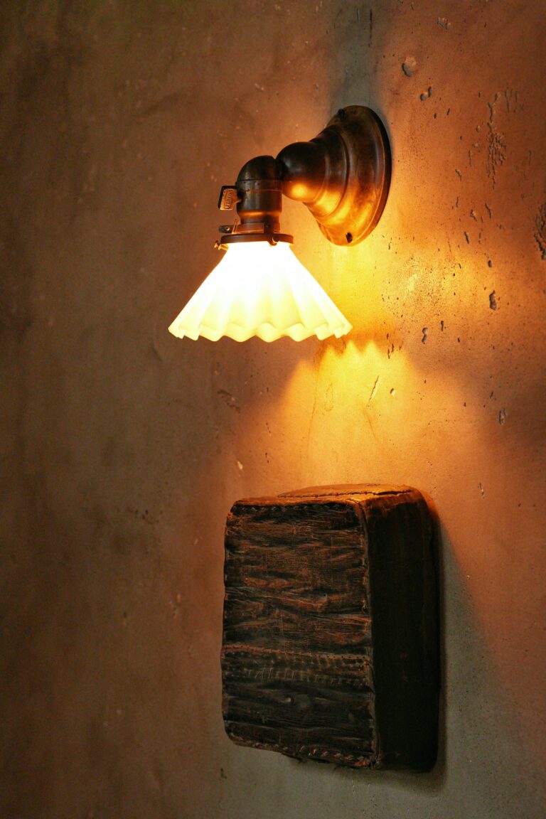 Warm glow from a vintage wall lamp against a rustic wall setting indoors.