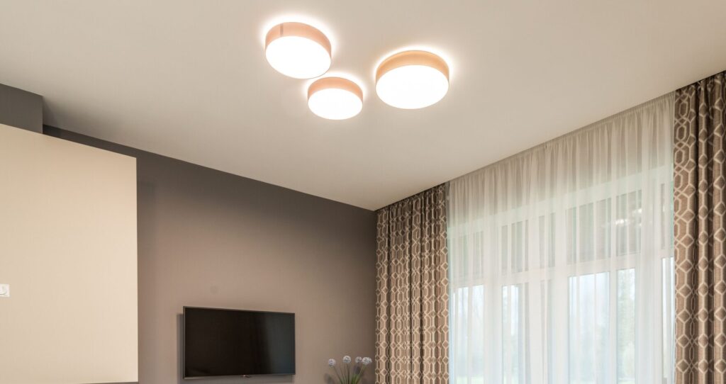 Interior of modern flat with spacious lounge and sofa with pillows under luminous lamps