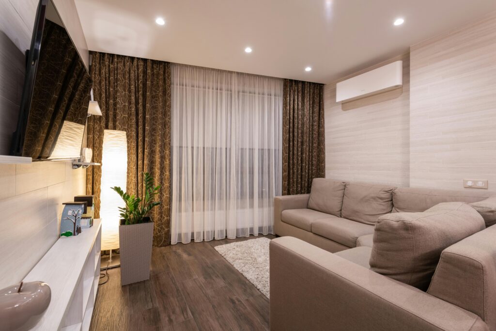 A stylish and cozy living room featuring a sofa, wooden flooring, and soft lighting.
