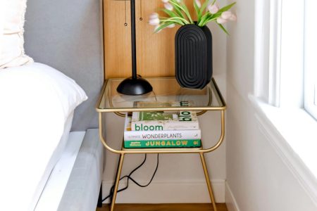 How To Choose The Perfect Nightstands For Your Bedroom Stylish bedroom nightstand with a black lamp, books, and a vase of flowers.